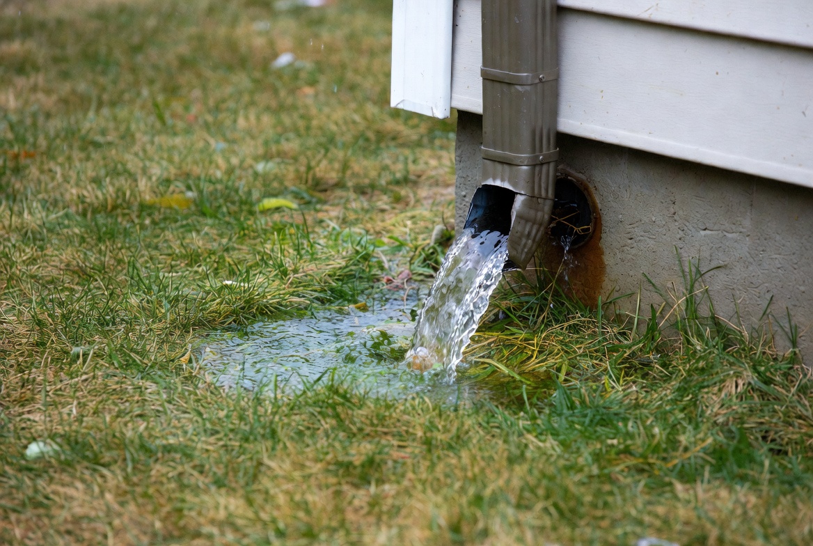 residential downspout outlet during winter rain