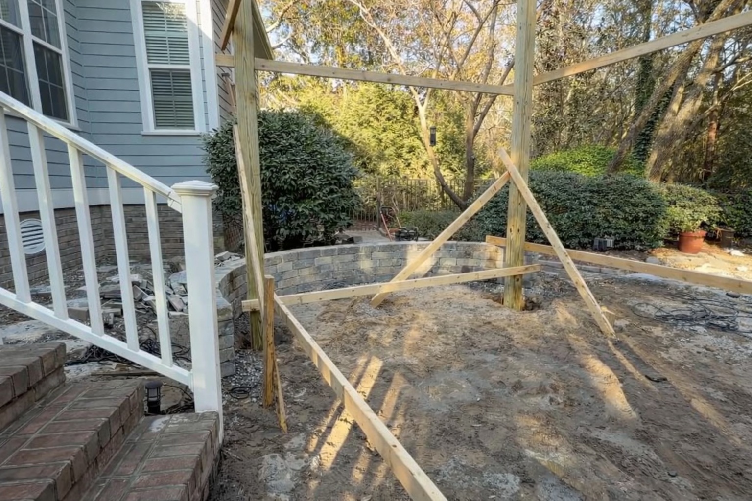 Precision Hardscape crew building a curved seat wall and paver patio in a coastal Carolina backyard