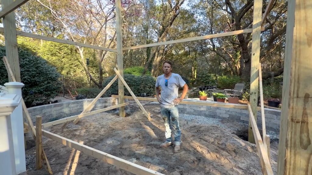 6x6 pergola posts set and braced — seat wall visible in the background with gravel base in place
