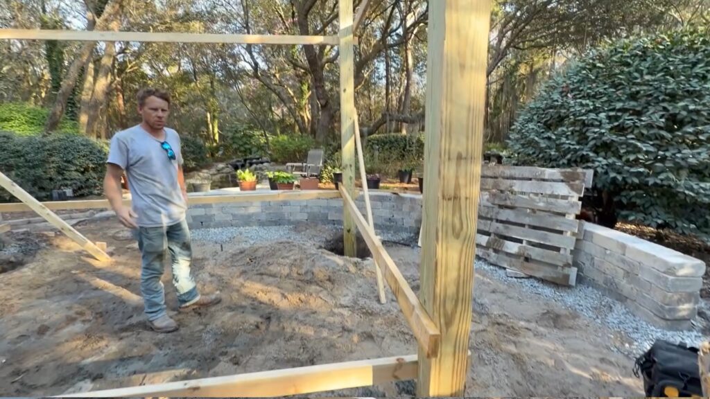 6x6 pergola posts set and braced — seat wall visible in the background with gravel base in place