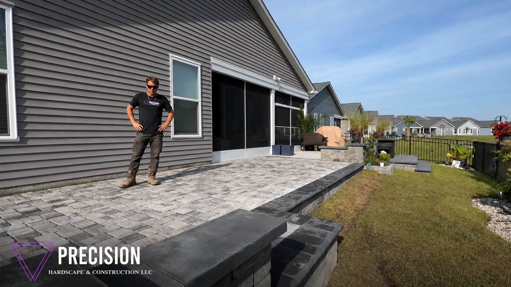 Raised paver patio with charcoal seat walls, retaining wall, and contrast caps off a screened porch — Precision Hardscape & Construction, coastal Carolina