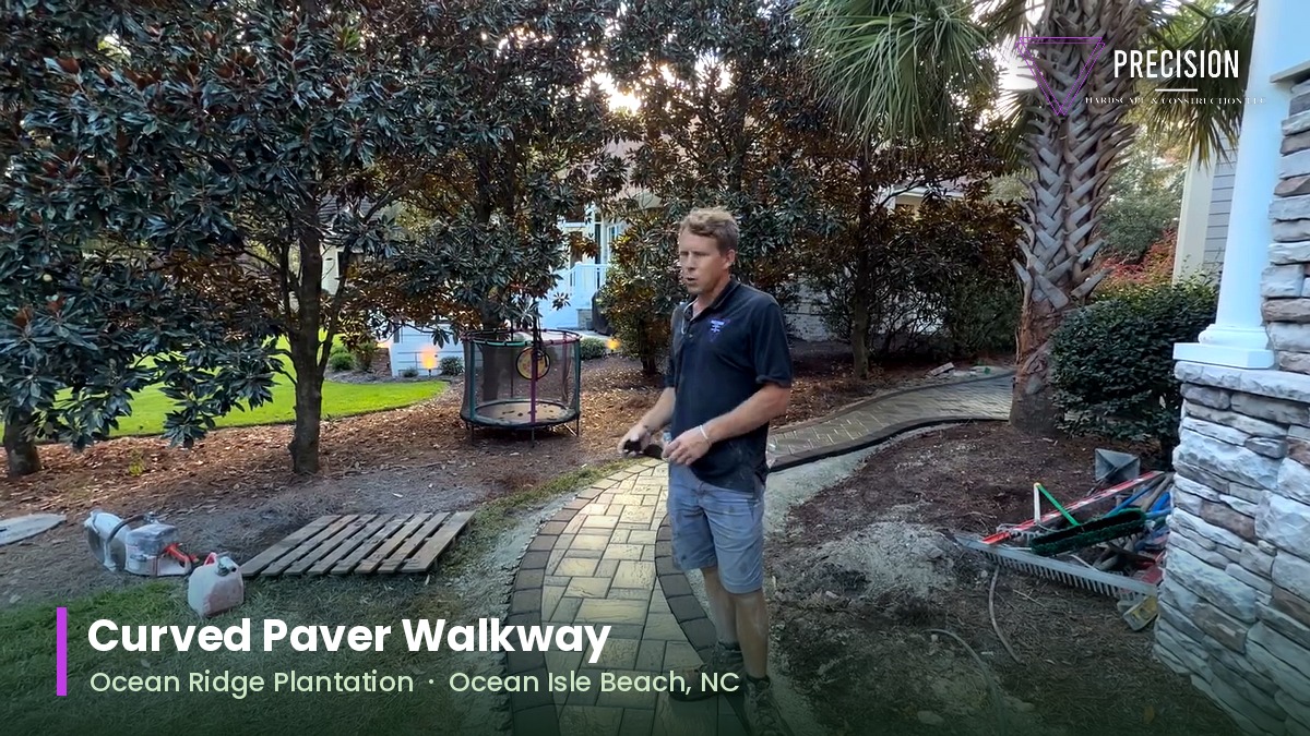 Curved paver walkway with a dark soldier course border sweeping through a landscaped yard at Ocean Ridge Plantation, Ocean Isle Beach NC