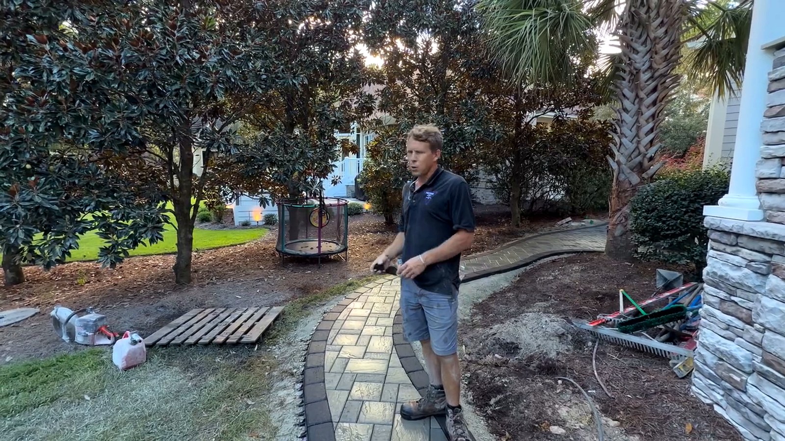 Finished curved paver walkway with dark soldier course border sweeping through a landscaped coastal yard in Ocean Ridge Plantation NC
