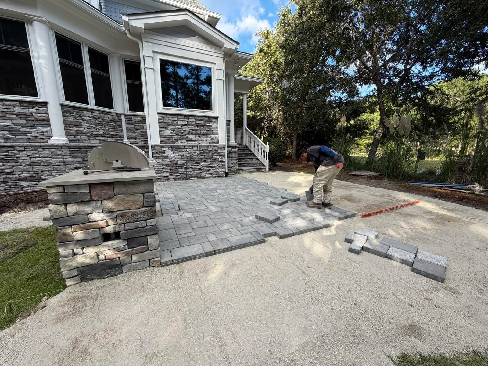 Gray paver patio laid tight to a stacked stone outdoor kitchen and grill island at a home near Ocean Isle Beach NC