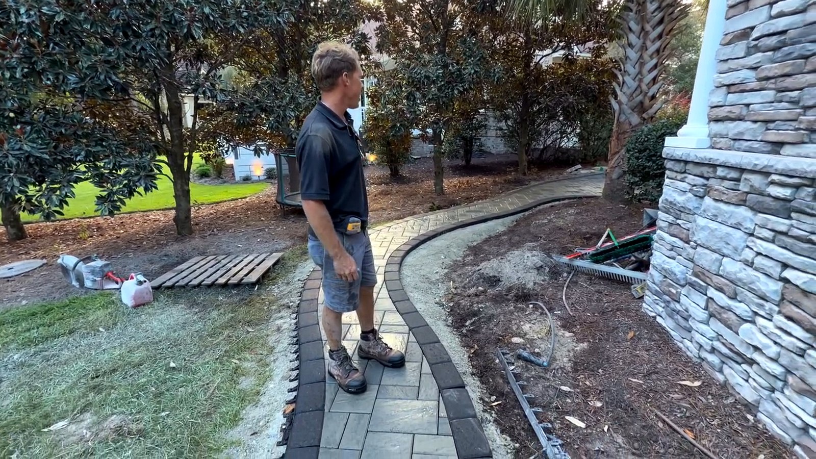 Curved paver walkway running between planting beds toward a stone column at a home near Ocean Isle Beach North Carolina